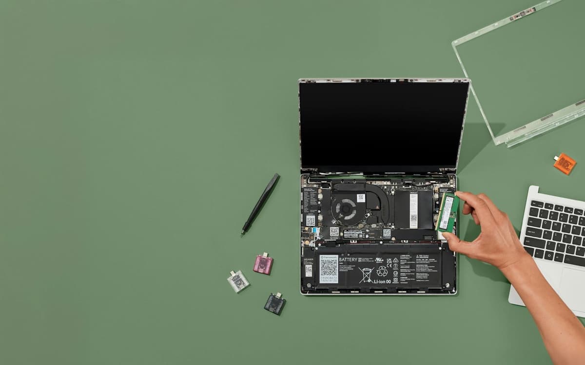 Framework Laptop 13 opened and disassembled on a green background, showing its modular, user-replaceable internal components